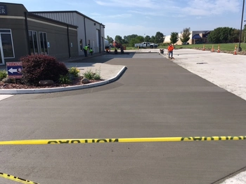 A freshly poured concrete driveway drying in front of the ImpactLife Burlington location. Lowes is visible in the background.